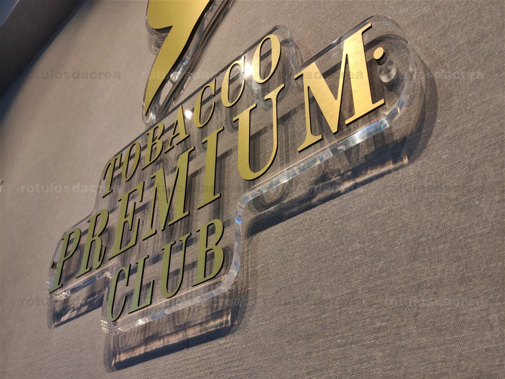 Logo de aluminio composite dorado cepillado sobre base de metacrilato transparente