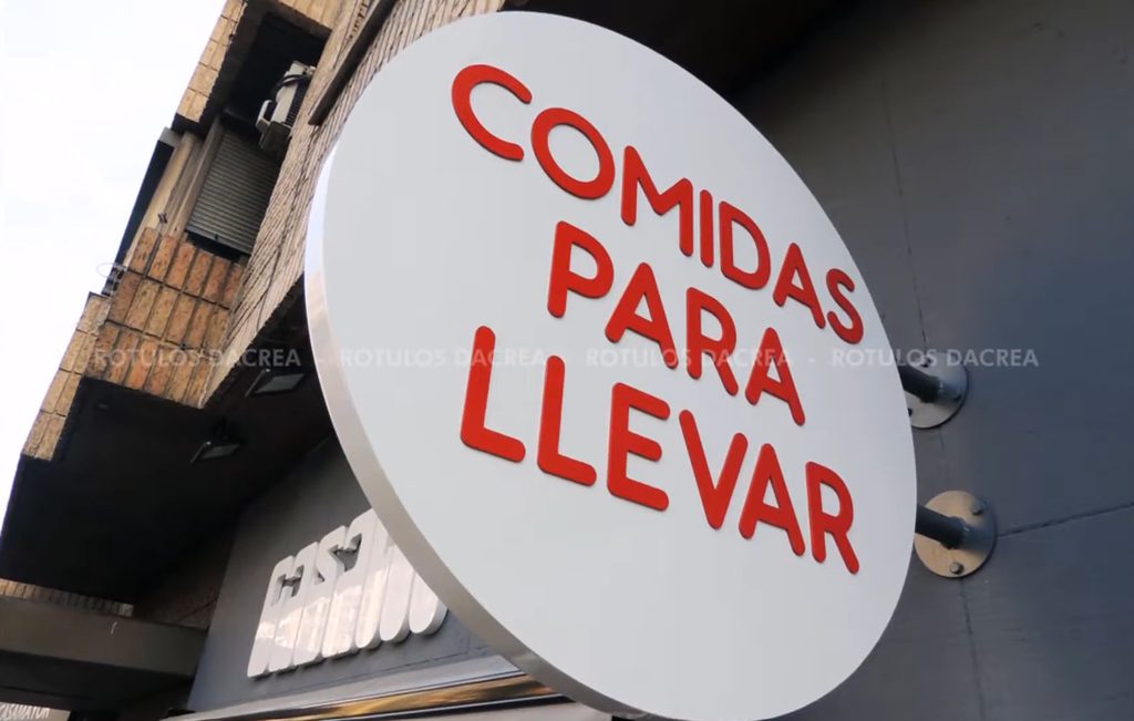 Banderola circular blanca con letras corpóreas rojas de comidas para llevar en la fachada de Casaní