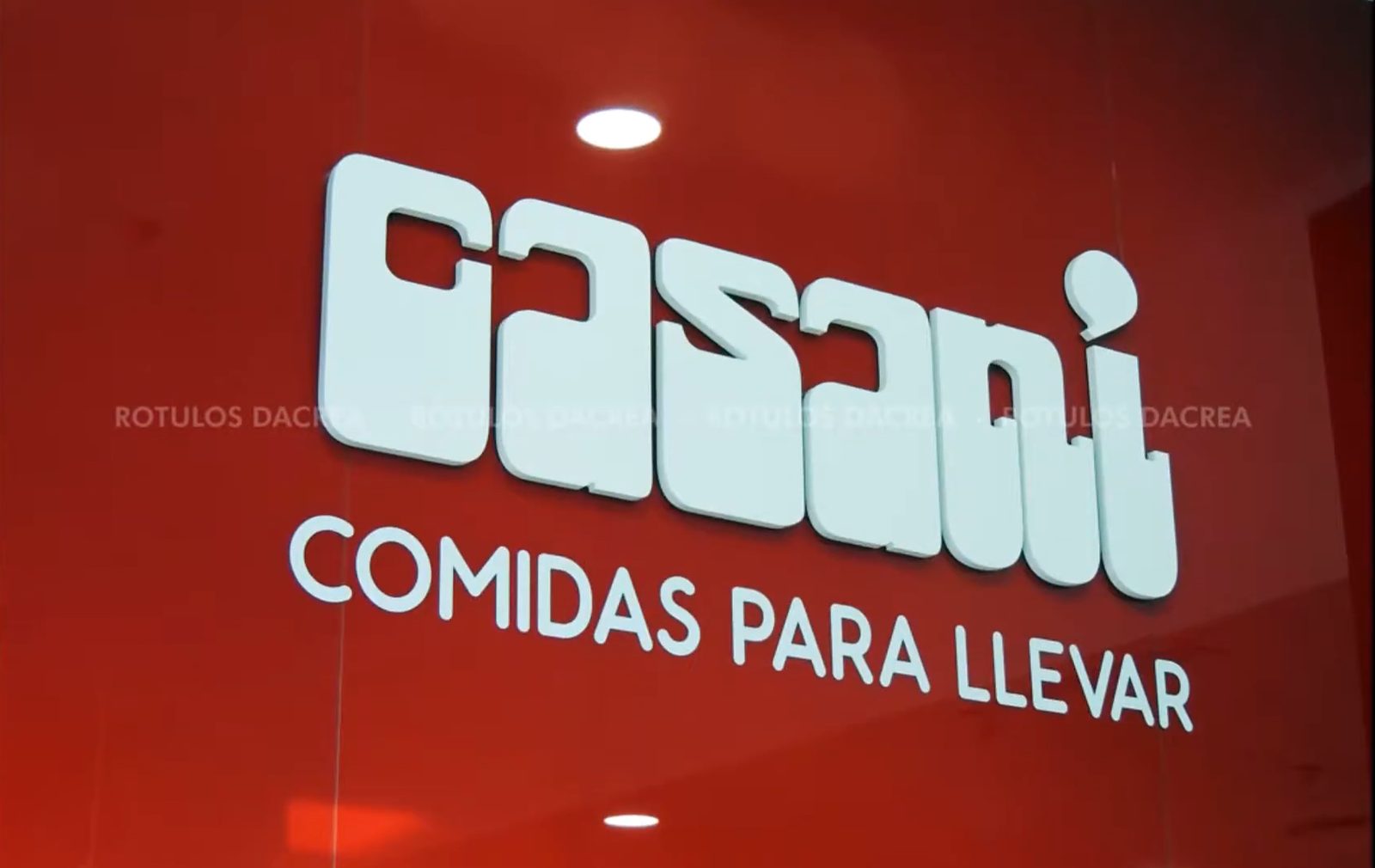 Detalle del logotipo de Casaní en letras corpóreas blancas sobre la pared roja del local
