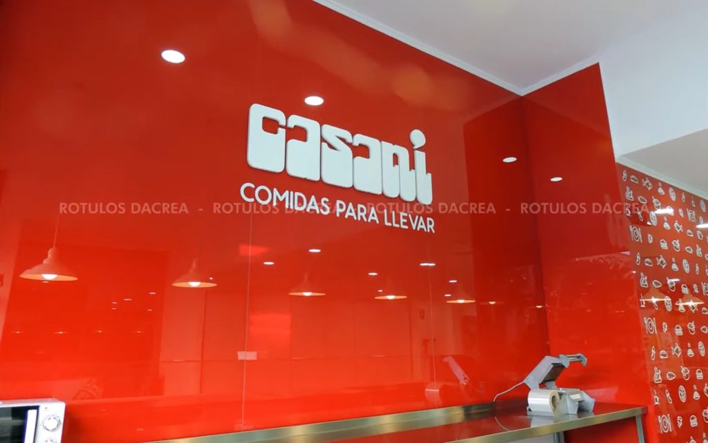 Logotipo de Casaní en letras corpóreas blancas sobre la pared roja del interior del local