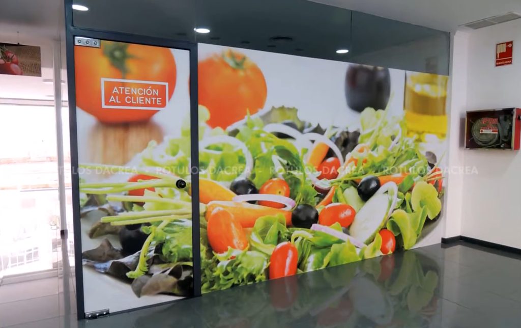 Mampara de cristal cubierta con vinilo impreso y el rótulo de atención al cliente integrado