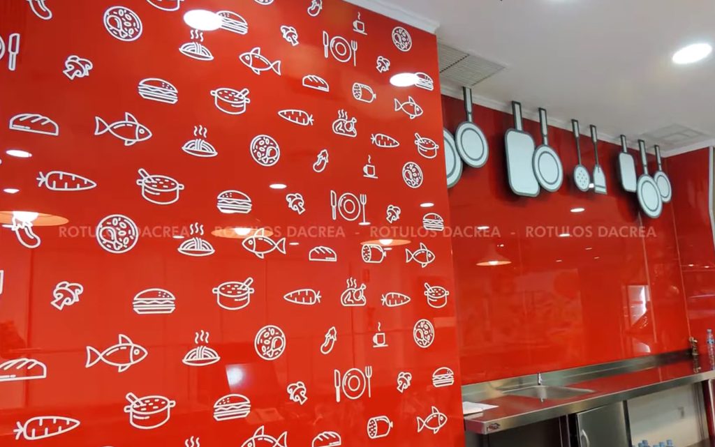 Trama de pictogramas de cocina en vinilo blanco sobre la pared roja del local de Casaní