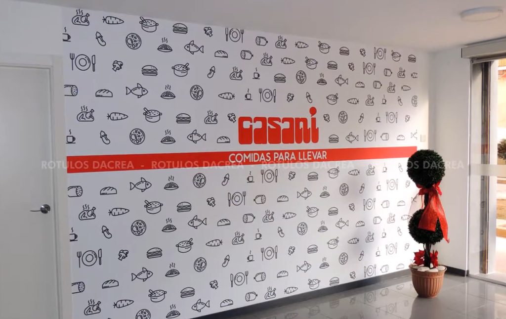 Pared blanca con pictogramas en vinilo, el logotipo de Casaní y una banda roja con el reclamo